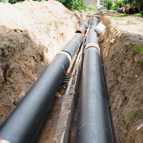 Plumbing repair. Installation of new industrial street water pipes in dug hole in two lines, outdoor